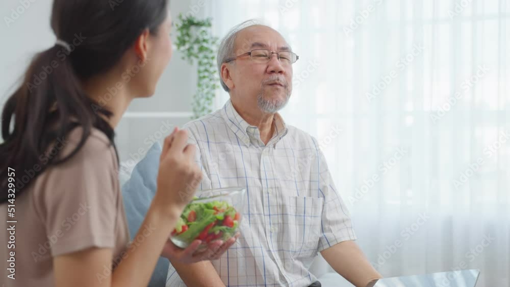 Asian senior elderly father eat salad with daughter in kitchen at home Asian senior elderly father eat salad with daughter in kitchen at home