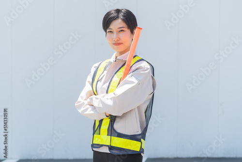 誘導棒を持ち作業服を着る日本人女性 photo