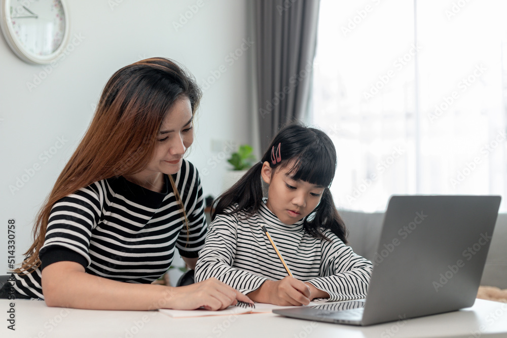 Asian little young girl kid learning online class at home with mother ...