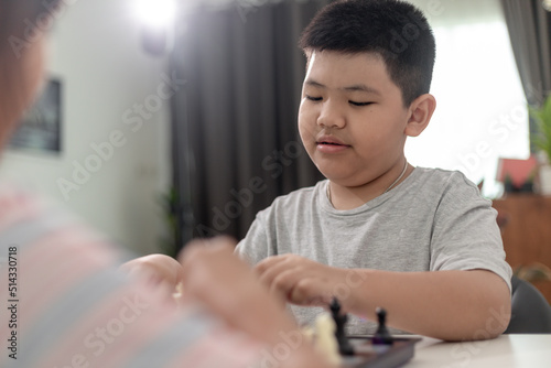 Little boy and little girl are playing chess at home.Children playing chess
