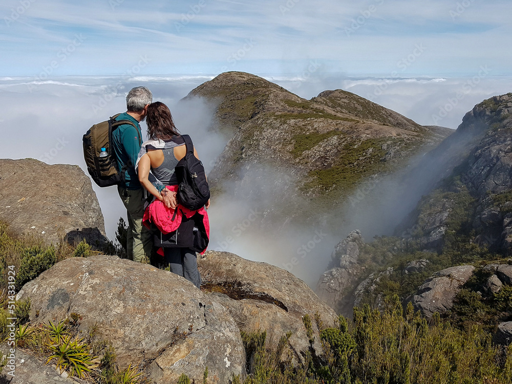 Couple with backpack contemplating mountains covered by clouds in Serra do Caparaó