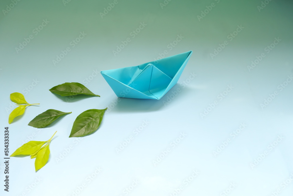 Clean energy for sea and cargo transportation and travel and sustainable maritime transport concept. Paper boat emitting fresh green leaves.