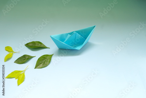 Obraz na płótnie Clean energy for sea and cargo transportation and travel and sustainable maritime transport concept. Paper boat emitting fresh green leaves. w salonie