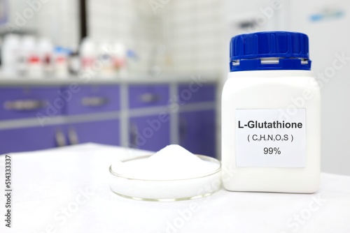 Selective focus of a bottle of pure glutathione chemical compound or l-glutathione whitening beside a petri dish with powder. White Chemistry laboratory background with copy space. photo