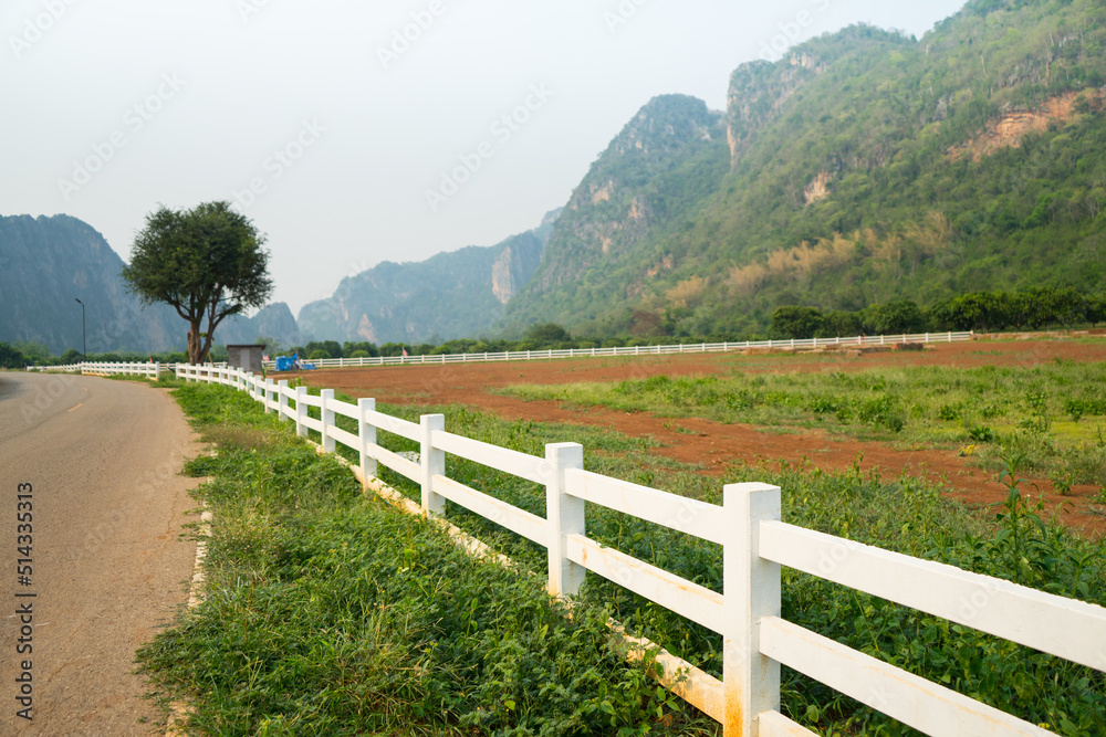 White concrete fence around the agriculture farm or ranching near the complicated mountain with road and sunlight background at the Ban Rai ,Uthai Thani, Thailand. White concrete fence around the agriculture farm or ranching near the complicated mountain with road and sunlight background at the Ban Rai ,Uthai Thani, Thailand.