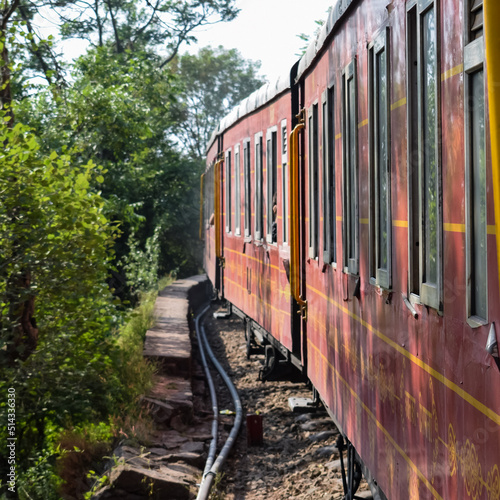 Toy Train moving on mountain slopes, beautiful view, one side mountain, one side valley moving on railway to the hill, among green natural forest. Toy train from Kalka to Shimla in India