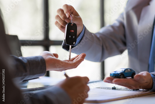 Hand of businessman Smiling car salesman handing over your new car keys  dealership and sales gives the car key concept