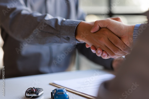 Car rental service sales give the car key concept. Close up view Hand of agent handshake to the customer after signing rental contract form.