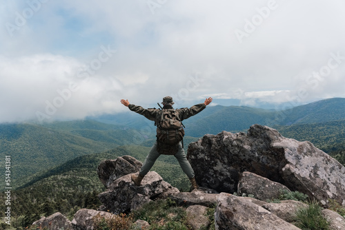 A man stands on top of a mountain and enjoys a beautiful mountain view. Taken on top of Mount Pidan, Russia. High quality photo