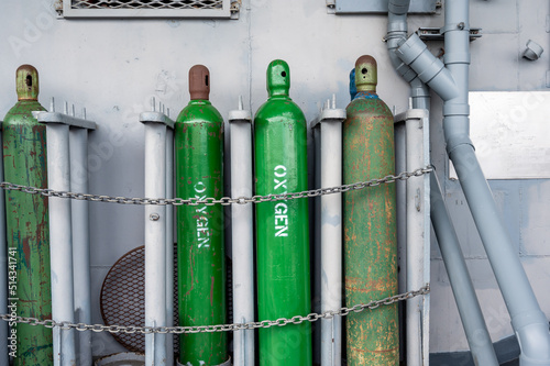 Compressed gas cylinders being stored vertically secured by a metal chain and a metal cap.