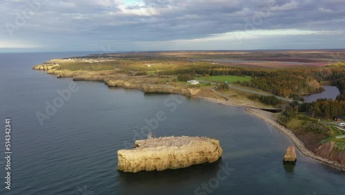 Slow motion drone footage on the scenic shoreline of Caraquet, New Brunswick, Canada. Scattered clouds and blue sky over landscape in fall colors.