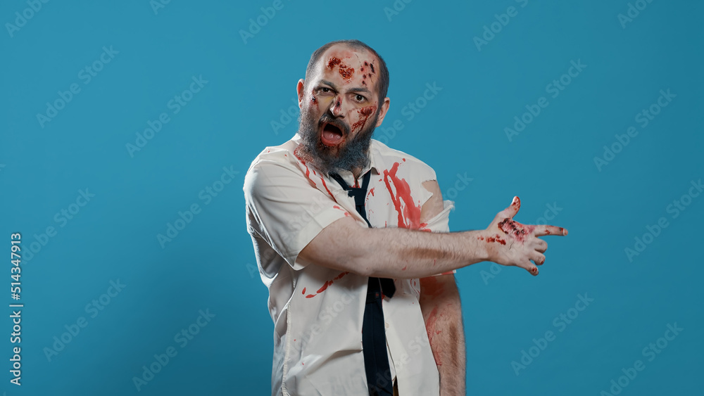 Horror looking monster pointing on right side of background. Spooky brain dead walking dead corpse gesturing with finger on right while looking and growling at camera. Studio shot
