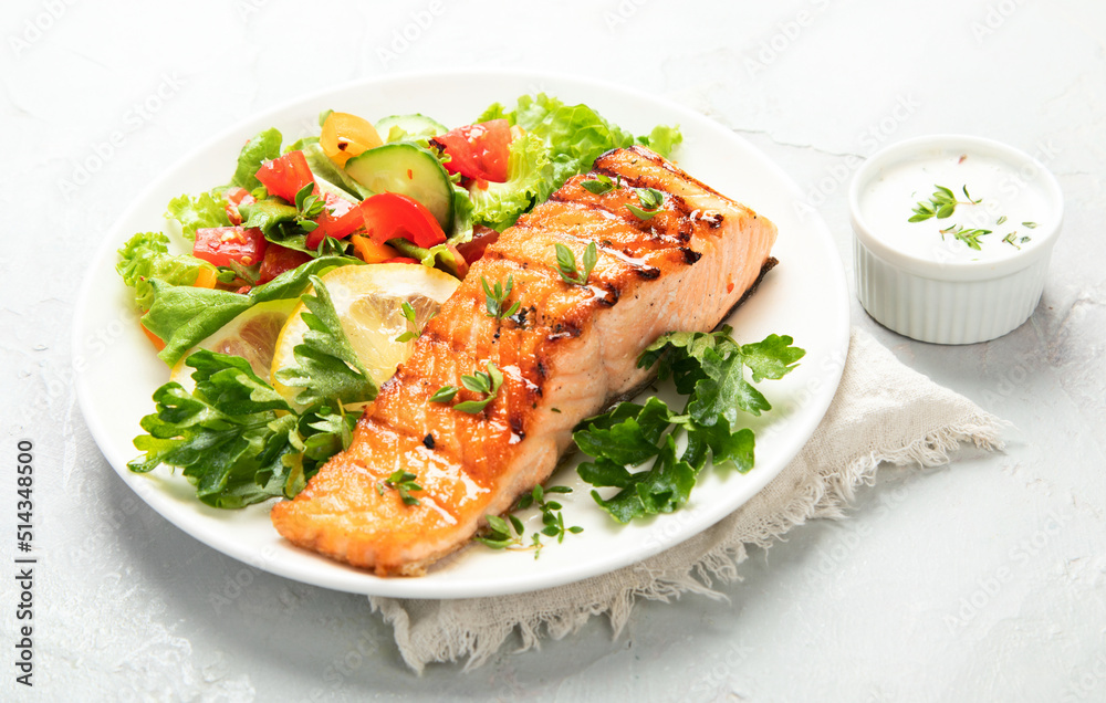 Salmon steak with vegetables and fries on light background. Salmon steak with vegetables and fries on light background.