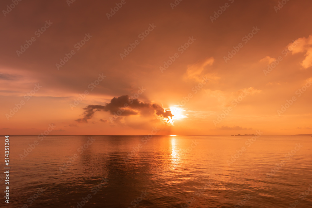 Stunning sun rising on horizon reflecting on a calm sea, clouds and sea in pink yellow colors. New day concept.