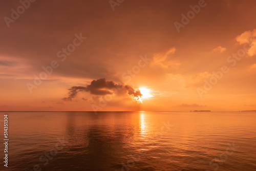 Stunning sun rising on horizon reflecting on a calm sea  clouds and sea in pink yellow colors. New day concept.