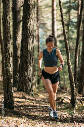 Young woman in sportswear enjoy trail running and working out in the forest