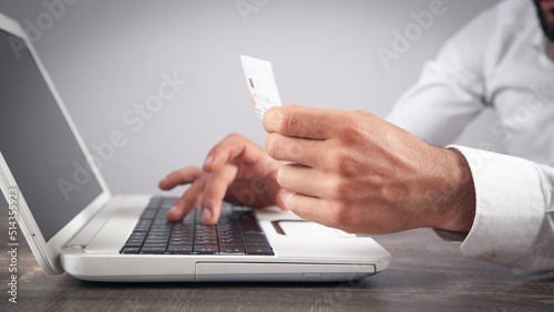 Businessman using laptop computer and holding credit card.