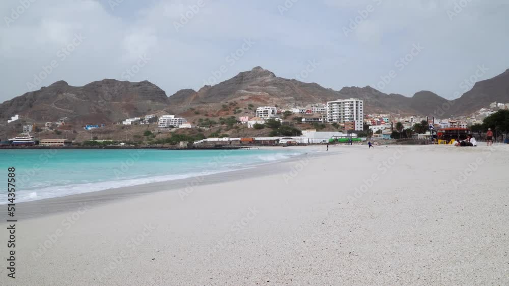 Turquoise ocean waves rolling in slow motion to the white sandy beach with huge rock in the background Turquoise ocean waves rolling in slow motion to the white sandy beach with huge rock in the background