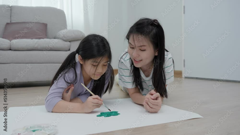 A mother is encouraging her daughter to draw her first picture on a family holiday. Drawing because it is a new activity to enhance the development of children. family activities. A mother is encouraging her daughter to draw her first picture on a family holiday. Drawing because it is a new activity to enhance the development of children. family activities.