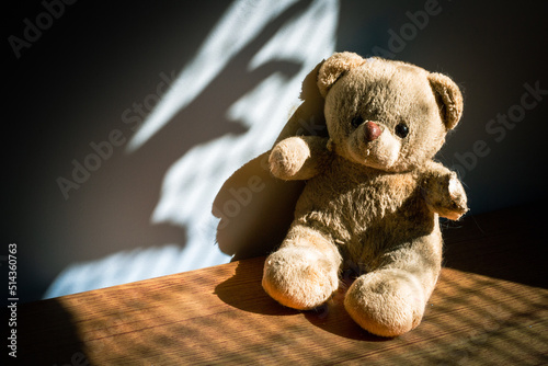 Foto Damaged and dirty teddy bear under casted shadow, representing a child in a bad