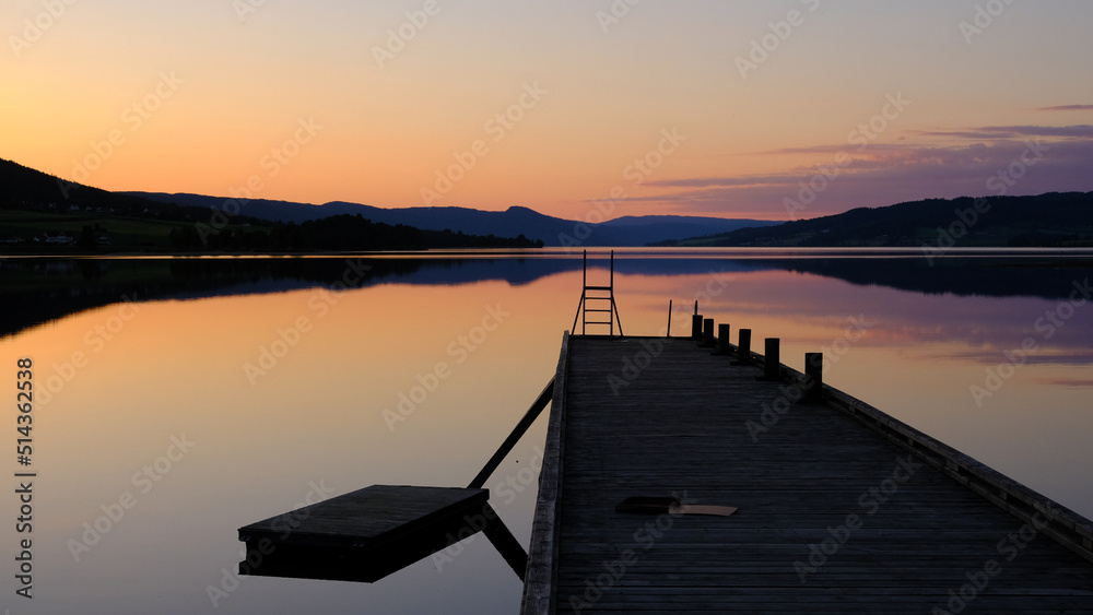 Obraz premium Norwegian lake at sunset with silhouette of pier, Jevnaker, Norway