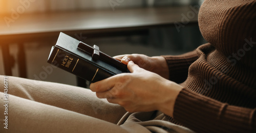 A woman praying holding a Holy Bible and pray to God.