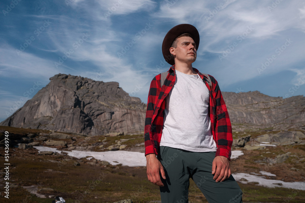 Naklejka premium Young traveler tourist dressed as hipster with backpack walks in mountains