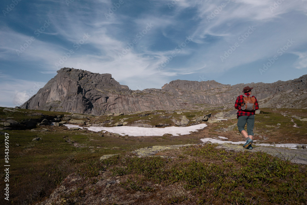 Young traveler tourist dressed as hipster with backpack walks in mountains