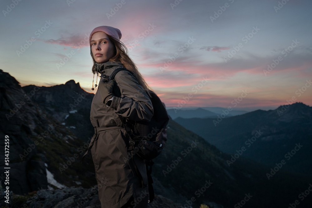 Young beautiful girl tourist with backpack in mountains in late evening after climbing rock Young beautiful girl tourist with backpack in mountains in late evening after climbing rock
