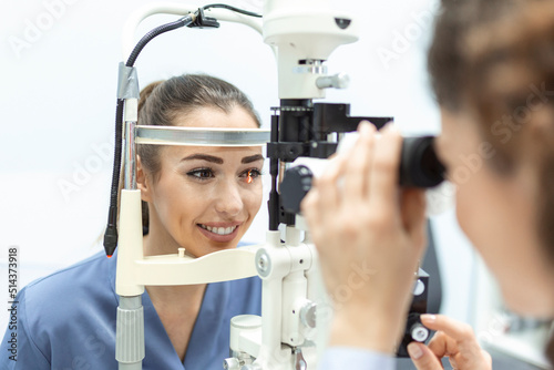 Eye doctor with female patient during an examination in modern clinic. Ophthalmologist is using special medical equipment for eye health