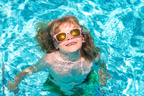 Child swim in summer pool water. Summer vacation fun. Cute kid in swimming pool.