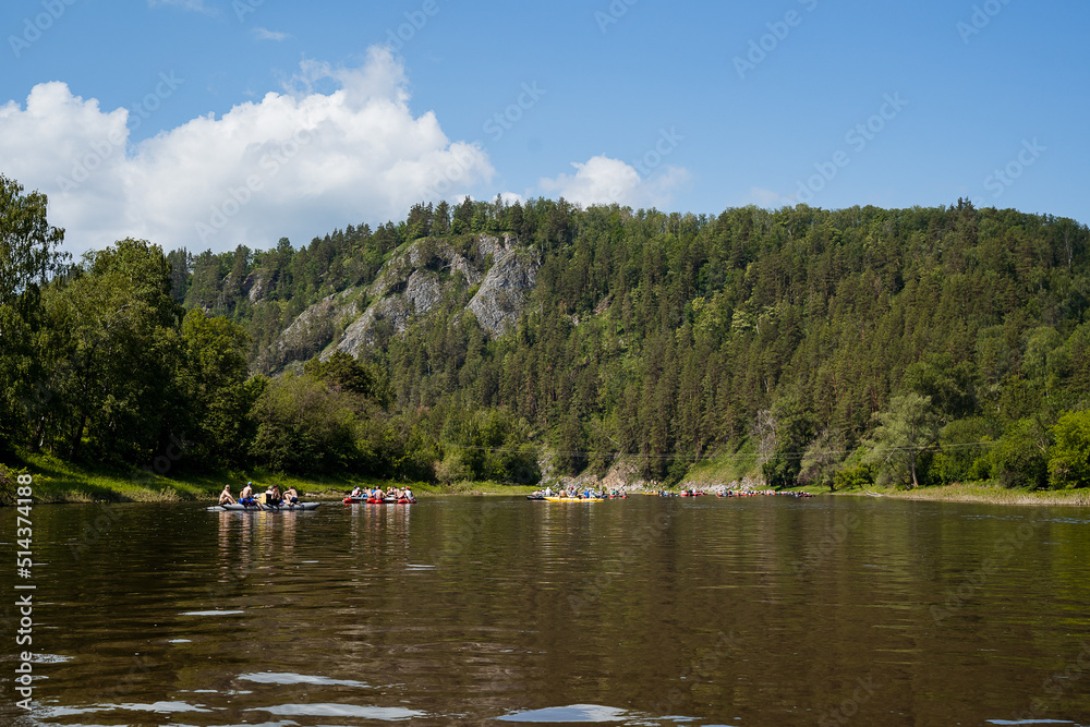Summer holidays on the water, water sports, people rafting on catamarans on a mountain river, a green forest in the mountains, sunny weather. Summer holidays on the water, water sports, people rafting on catamarans on a mountain river, a green forest in the mountains, sunny weather.