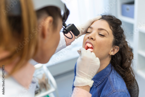 Female patient opening her mouth for the doctor to look in her throat. Otolaryngologist examines sore throat of patient.
