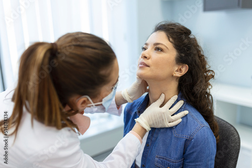 Endocrinologist examining throat of young woman in clinic. Women with thyroid gland test . Endocrinology, hormones and treatment. Inflammation of the sore throat photo