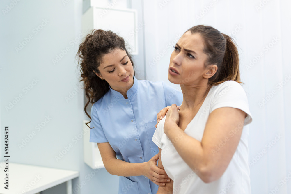 Woman doctor osteopath in medical uniform fixing woman patients shoulder and back joints in manual therapy clinic during visit. Professional osteopath during work with patient concept Woman doctor osteopath in medical uniform fixing woman patients shoulder and back joints in manual therapy clinic during visit. Professional osteopath during work with patient concept