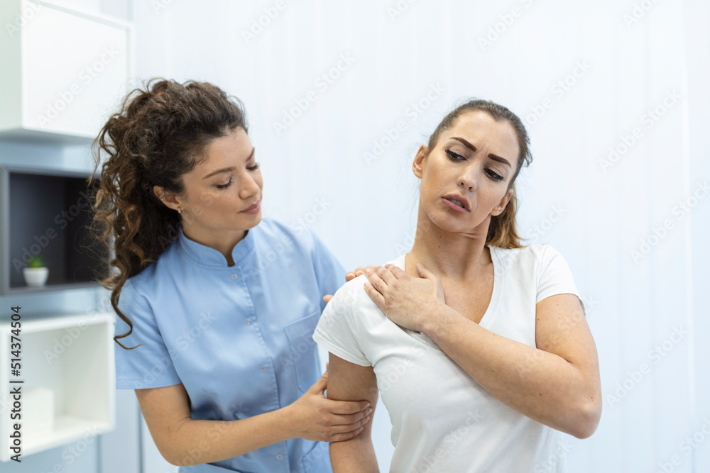 Woman doctor osteopath in medical uniform fixing woman patients shoulder and back joints in manual therapy clinic during visit. Professional osteopath during work with patient concept Woman doctor osteopath in medical uniform fixing woman patients shoulder and back joints in manual therapy clinic during visit. Professional osteopath during work with patient concept