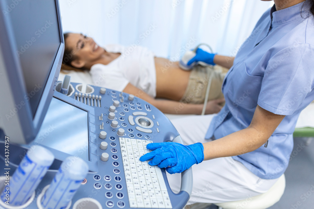 Obraz premium Ultrasound diagnostic of stomach on abdominal to woman in clinic, closeup view. Doctor runs ultrasound sensor over patient's girl tummy and looks at image on screen. Diagnosis of internal organs.