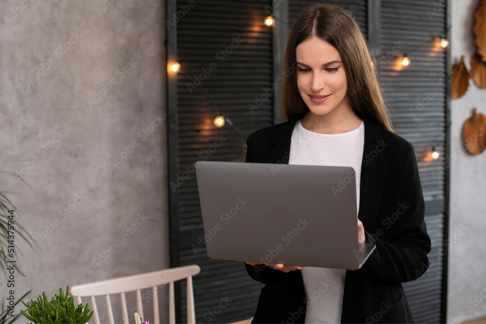 Smiling brunette woman using laptop computer over gray background Smiling brunette woman using laptop computer over gray background