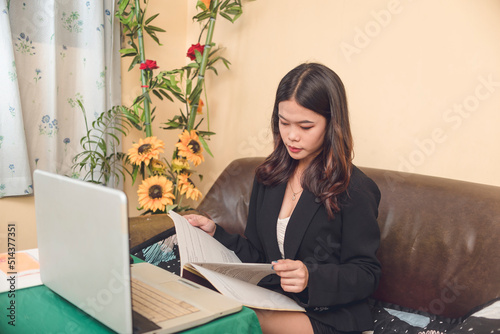 A young online teacher working remotely reviews a handbook for an upcoming topic. Professional home-based work. photo