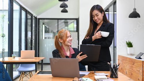 Two female colleagues discussing about new project together at co working space