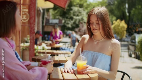 two young women girlfriends enjoy delicious cocktails in a cafe, spend time in a place, lifestyle in summer.