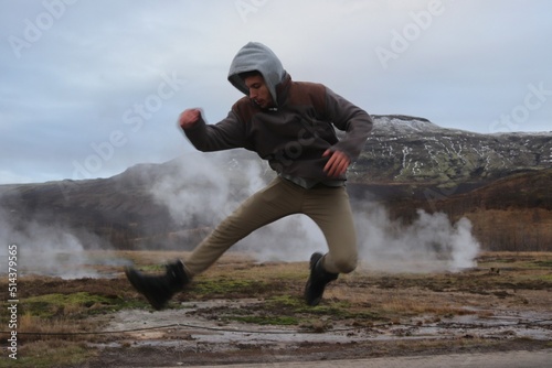 Man jumping behind Icelandic geyser. photo