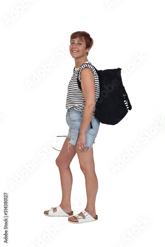 side view of a middle aged woman on a summer day with backpack lookig at camerra on white background photo