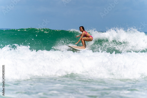 Asian woman surfer surfing and riding surfboard  the wave in the sea at tropical beach in sunny day. Healthy female enjoy outdoor activity lifestyle and water sport exercise surfing on summer vacation © CandyRetriever 