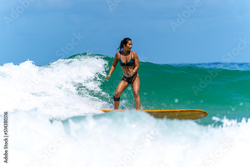 Asian woman surfer surfing and riding surfboard  the wave in the sea at tropical beach in sunny day. Healthy female enjoy outdoor activity lifestyle and water sport exercise surfing on summer vacation © CandyRetriever 