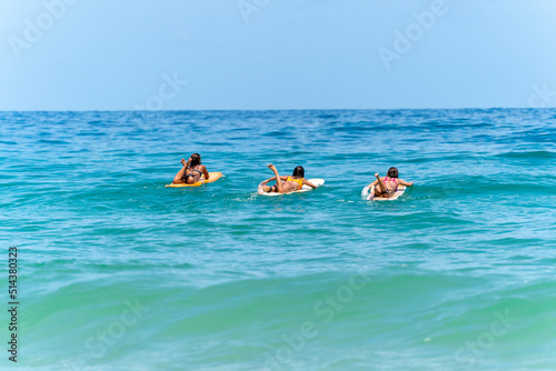 Photography Group of Asian woman surfer paddling surfboard and riding the wave in the sea at tropical beach in sunny day