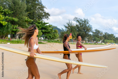 Photography Group of Asian woman surfer in swimwear holding surfboard walking together on tropical beach at summer sunset
