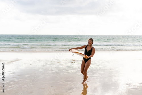 Photography Portrait of Young Asian woman surfer in swimwear holding surfboard walking on tropical beach at summer sunset