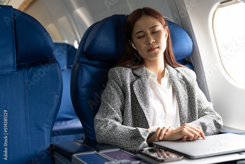 Tired business asian lady napping on seat while traveling by airplane. Commercial transportation by planes.