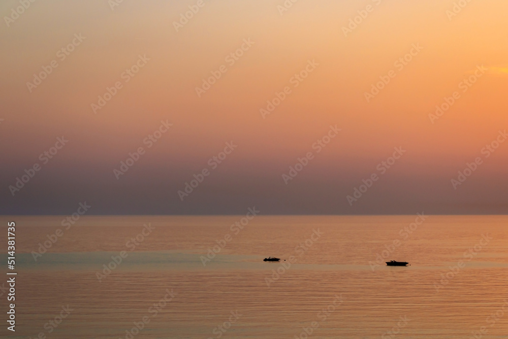 Beautiful colorful sunset over Mediterranean Sea with small speedboats